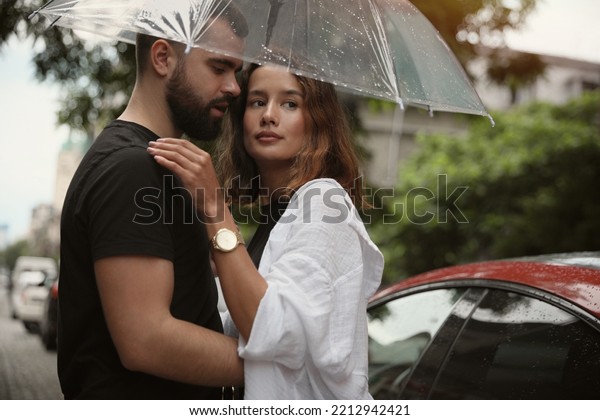 Young couple with umbrella\
enjoying time together under rain on city street, space for\
text