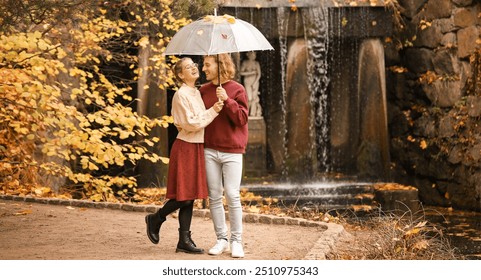 Young couple with umbrella in park on autumn day - Powered by Shutterstock