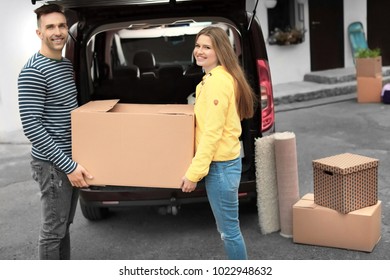 Young Couple Unloading Boxes From Their Car On Moving Day