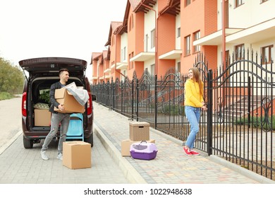 Young Couple Unloading Boxes From Their Car On Moving Day