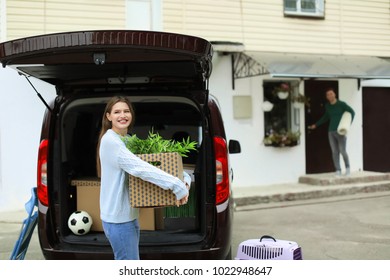 Young Couple Unloading Boxes From Their Car On Moving Day