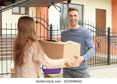 Young Couple Unloading Boxes From Their Car On Moving Day