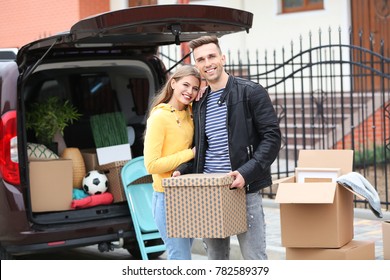 Young Couple Unloading Boxes From Their Car On Moving Day