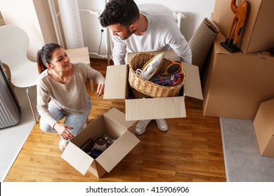 Young couple unpacking cardboard boxes at new home.Moving house.