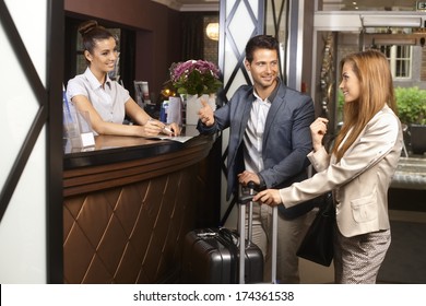 Young Couple Upon Arrival At Hotel Reception.