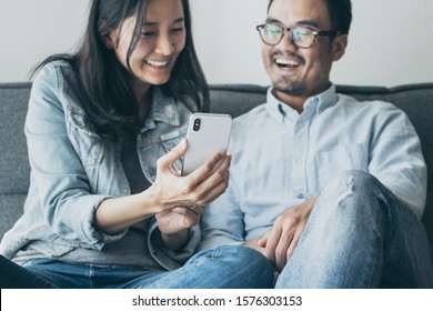 Young Couple Using Cell Phone.hand Holding Texting Message On Screen Mobile Chatting Friend ,search Internet Sitting On Sofa At Home.technology Device Contact Communication Connecting People Concept