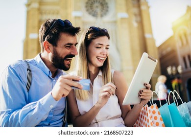 Young Couple Using Credit Card And Digital Tablet For Online Shopping Outdoor.