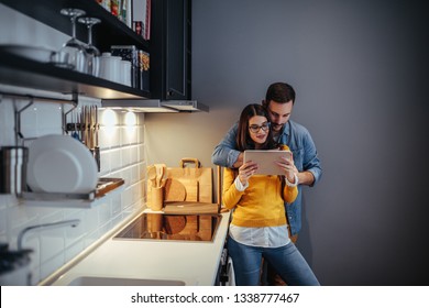 Young couple using digital tablet in their kitchen at home