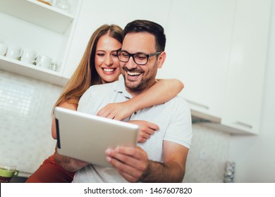 Young couple using digital tablet in the kitchen - Powered by Shutterstock