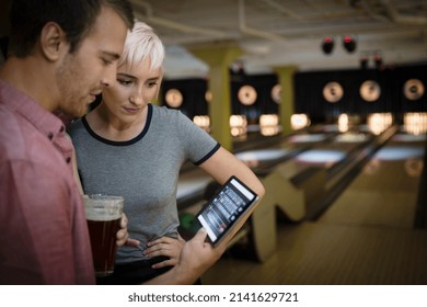 Young couple using digital tablet at bowling alley