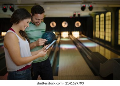 Young couple using digital tablet at bowling alley
