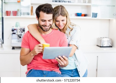 Young couple using digital tablet in the kitchen - Powered by Shutterstock