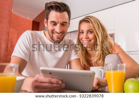 young couple using digital tablet at breakfast time