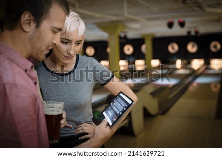 Young couple using digital tablet at bowling alley