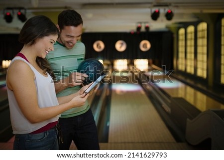 Young couple using digital tablet at bowling alley