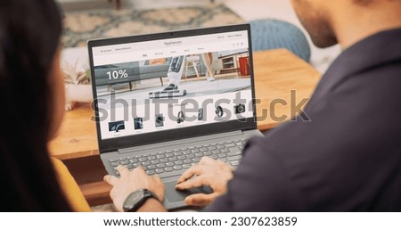 Young Couple Using Laptop to Buy Appliances From the Confort of Their Home: They are Browsing Internet, Doing Online Shopping, Choosing the Best Deal of Sale on Websites, Discussing the Decision Foto stock © 