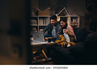 young couple using laptop computer at home. evening scene