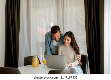 Young couple using laptop computer on the table in the living room and drinking orange juice