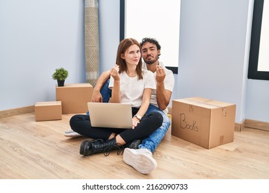 Young Couple Using Laptop At New Home Doing Money Gesture With Hands, Asking For Salary Payment, Millionaire Business 