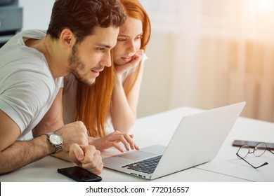 Young Couple Using Laptop On Desk At Home And Think