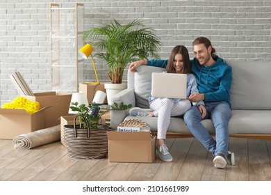 Young couple using laptop in their new house on moving day
