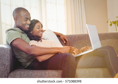 Young couple using a laptop while relaxing on a sofa in the living room