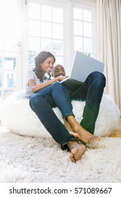 Young couple using a laptop while relaxing on a bean bag in the living room