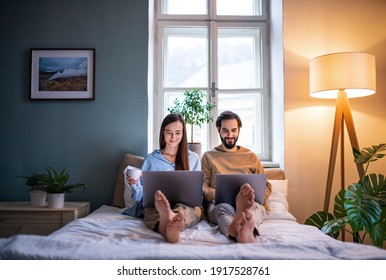 Young Couple Using Laptops On Bed Indoors, Home Office Concept.