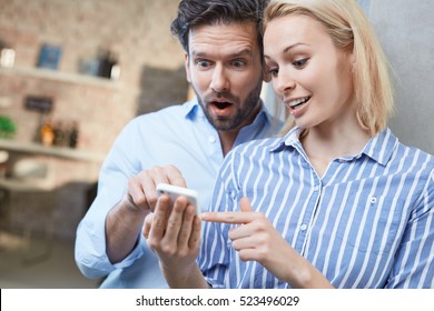 Young couple using mobile, looking at photos, looking wondering.