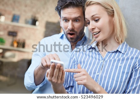 Young couple using mobile, looking at photos, looking wondering.