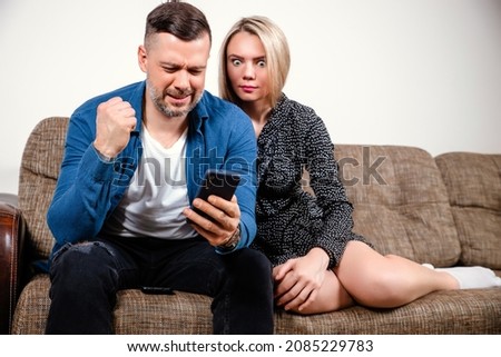 Young couple using smartphone, broken mobile phone, looking at screen, having financial problem, negative, worried, insufficient funds, reading bad news, hand on shoulder, mobile banking, messaging