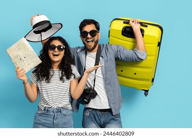 Young Couple Vacation. Adults Bright Yellow Suitcase, Showcasing Their Readiness For A Holiday Adventure. Both Wearing Sunglasses And Casual Summer Clothes, Against A Blue Background. - Powered by Shutterstock