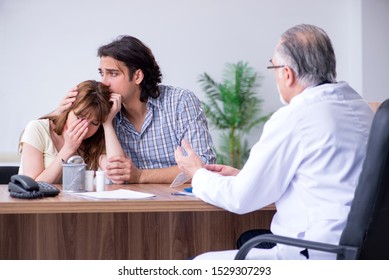 Young Couple Visiting Old Male Doctor