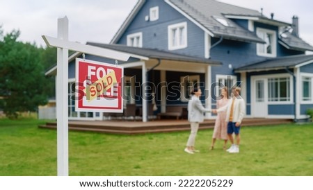 Young Couple Visiting a Potential New Home Property , SHaking Hands with Professional Real Estate Agent. Female Realtor Showing the Area to Future Homeowners. Focus on Sold Sign.
