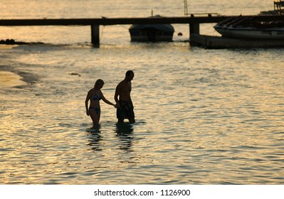 A Young Couple Wading Into The Sea, Moorea, Tahiti, French Polynesia, South Pacific