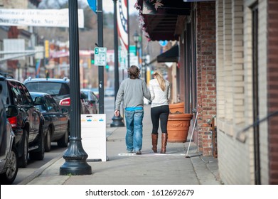 Young Couple Walking Away Down A Small Town Main Street