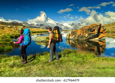  Young Couple Walking With Backpack And Camping Equipment On The Mountain Trail, Near Stellisee Lake, Valais Region, Zermatt, Switzerland, Europe