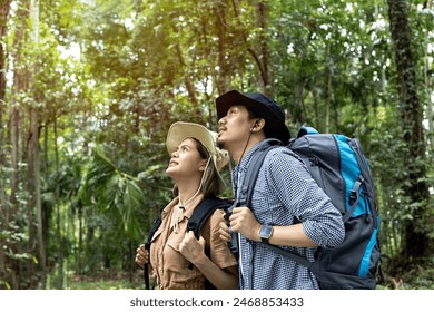 Young couple walking with backpacks in forest. Asian couple have fun together outdoors on a hike. travel, hiking, backpacking, tourism and people vacation trip concept - Powered by Shutterstock