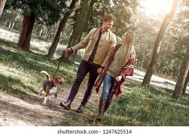 Young Couple Are Walking With Dog In Forest