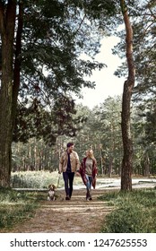 Young Couple Are Walking With Dog In Forest