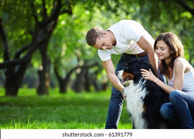 A Young Couple Walking A Dog In The Park