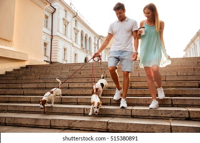 Young Couple Walking Down Stairs With Their Dogs On A City Street