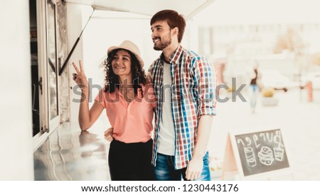 Young Couple Walking to Food Truck on Street. Promenade in Town. Girfriend and Boyfriend. Summer Day. Square in European City. Signboard on Street. Man in Shirt. Walking Young Woman.