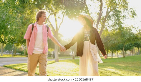 A Young Couple Walking Hand in Hand Through a Beautiful Sunlit Park on a Lovely Day - Powered by Shutterstock