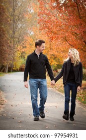 Young Couple Walking On A Path In Park Holding Hands