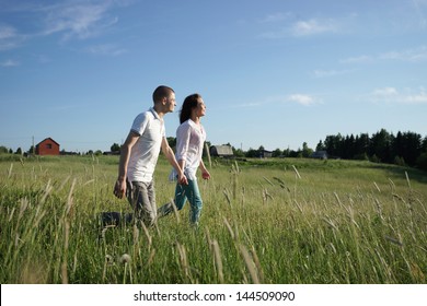 Young Couple Walking Through Green Field