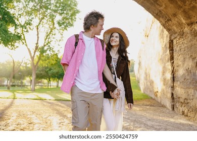 A Young Couple Walking Together in a Beautifully Sunlit Park, Enjoying Their Day - Powered by Shutterstock