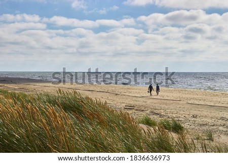 A young couple walks barefoot along the seashore after a storm