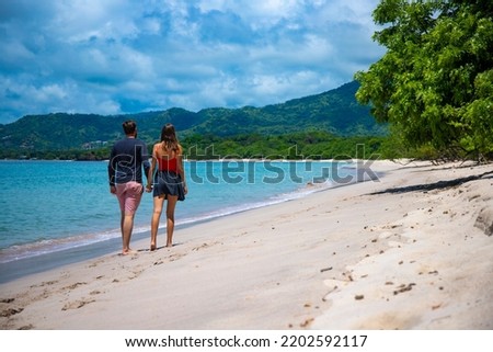 young couple walks holding hands on the beautiful beach in costa rica