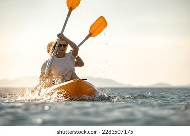 Young couple walks on sea kayak or canoe at calm sunset sea - Powered by Shutterstock